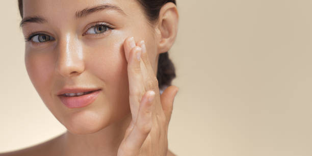 Woman applying facial moisturizer on her cheek