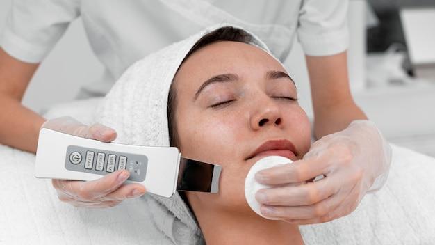 A woman receiving a facial treatment with a modern skincare device in a spa setting.