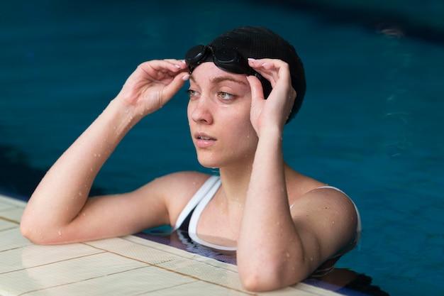 Female swimmer adjusting goggles at poolside