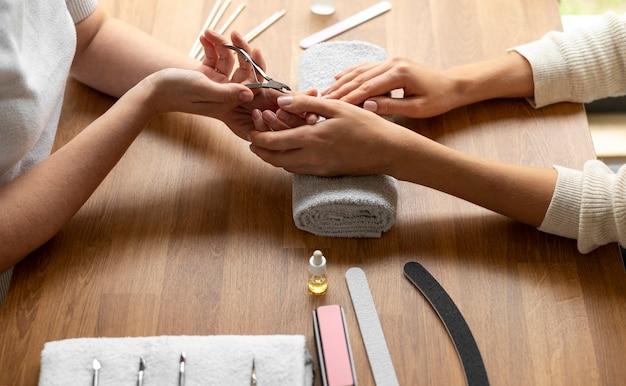 Manicure session with two people at a wooden table, focusing on nail care and manicure tools